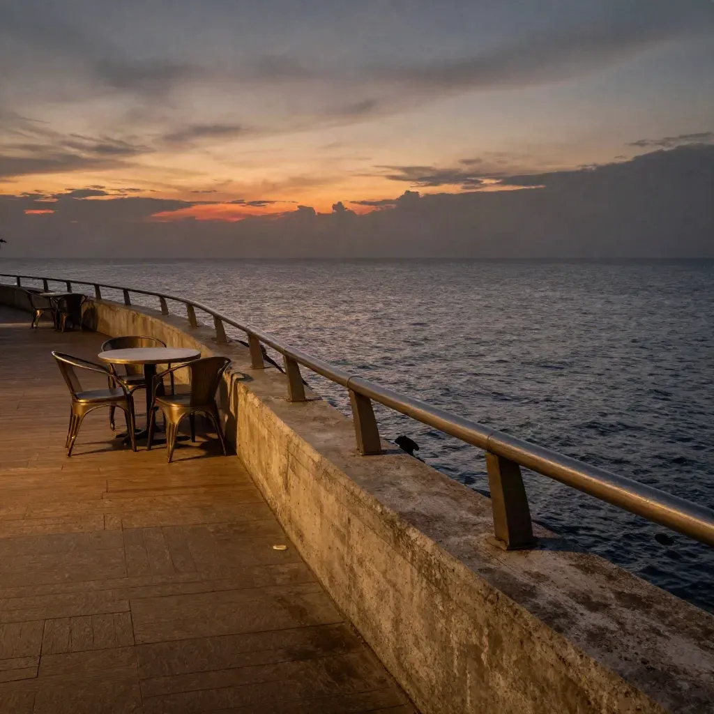 Promenade Teluk Cempedak waktu senja dengan meja kafe kosong dan pantulan laut.